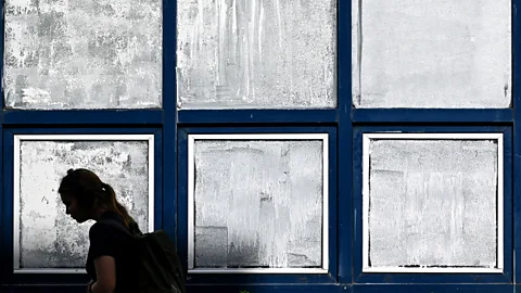 A silhouette of a woman walking past windows painted with white chalk paint (Credit: Getty Images)