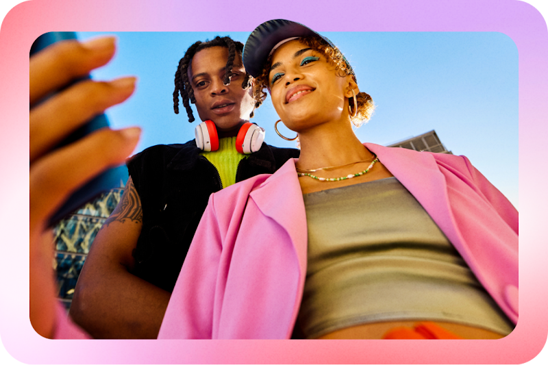 Image of two young people standing outside,  looking at a phone screen.